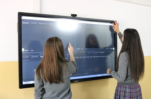 Alumnos y alumnas de primaria de INA sosteniendo una bandera de la paz con las banderas de todos los países
